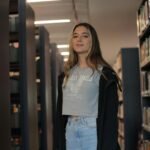 A young woman stands amidst library shelves, capturing the essence of learning.